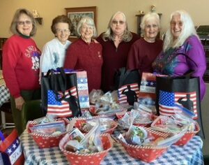 Large group picture behind table with gift baskets -Pictured (l-r): Auxiliary members Jenny Moch, Arlene Davis, CarolHumann, Sheri Brunner, Joy Hopkins, and Gloria Pederson