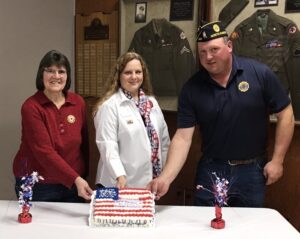 three people cutting a cake - Pictured (l-r): Birthday party attendees. Elaine Ackerman, Auxiliary President Unit 250; Candace Berg, Auxiliary Department President; Jon Metz, Legion Commander Post 250.