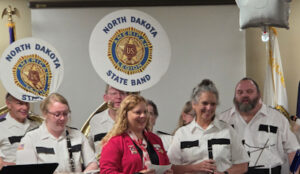 Department President Candace Berg (in pink)presenting an Auxiliary donation to North Dakota State Legion Band Manager Cathy Keogh (Pictured second from right) - band members with tubas
